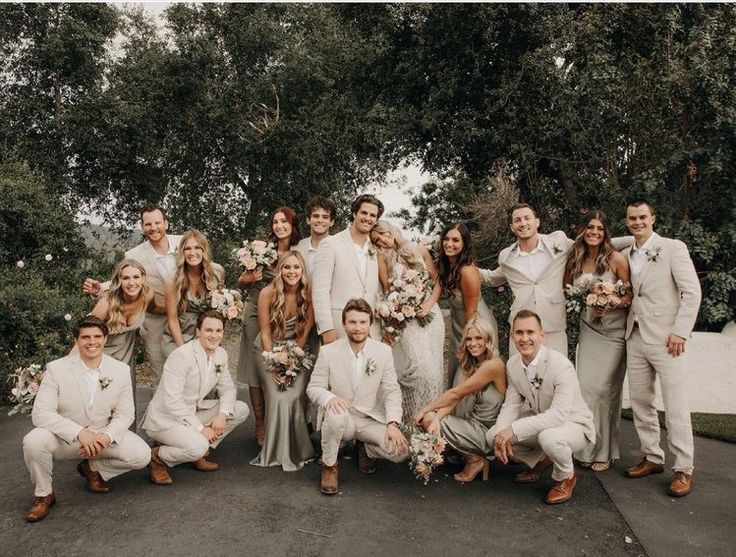 a group of people standing next to each other in front of some trees and bushes