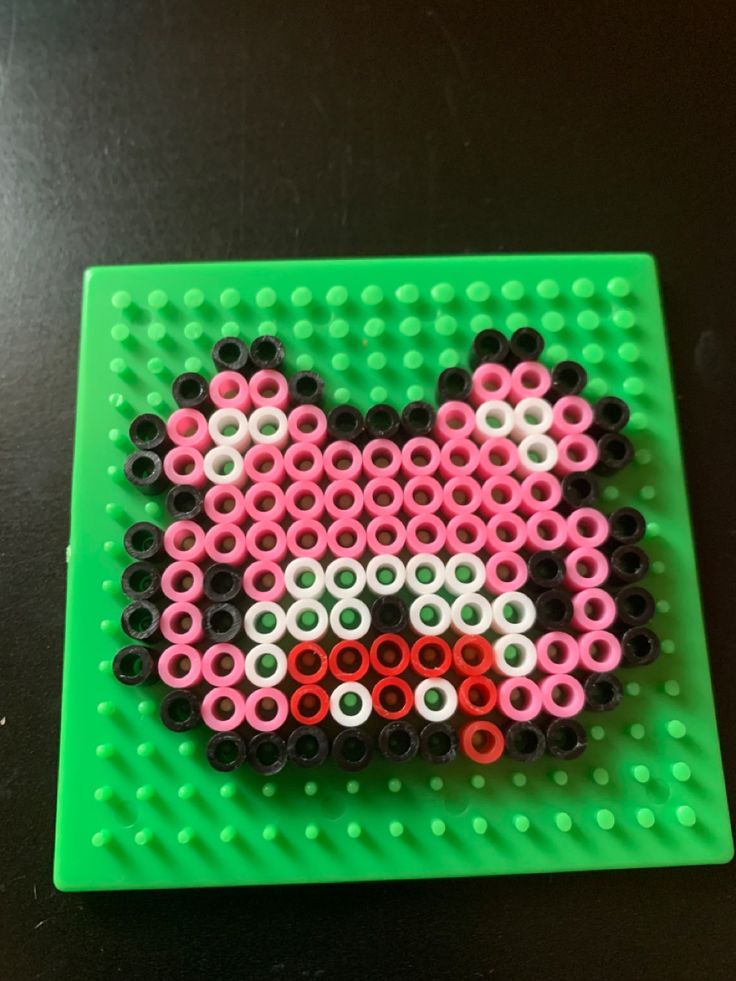 an image of a cat made out of legos on a green board with black and white dots