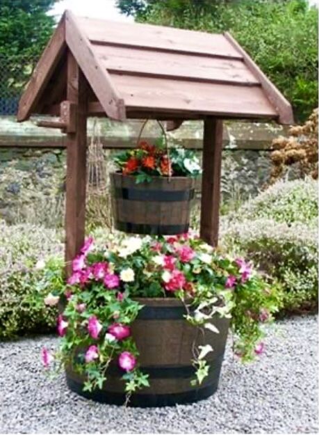 two buckets with flowers in them sitting on the ground next to a gazebo