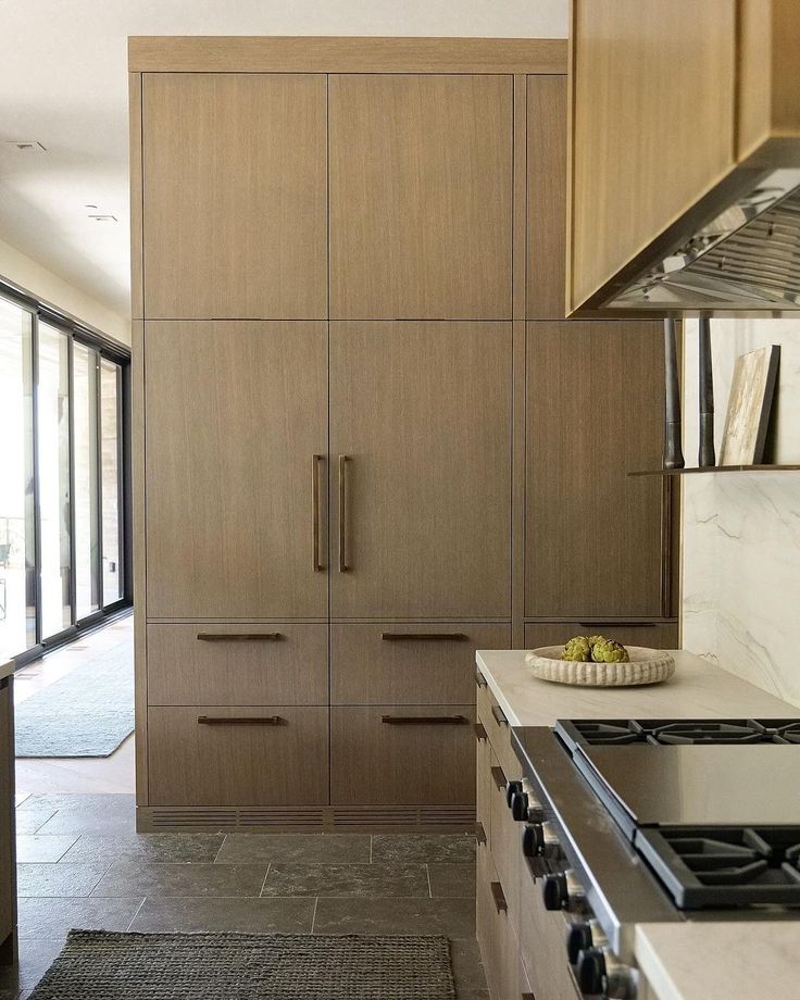 a kitchen with wooden cabinets and marble counter tops, along with a stove top oven