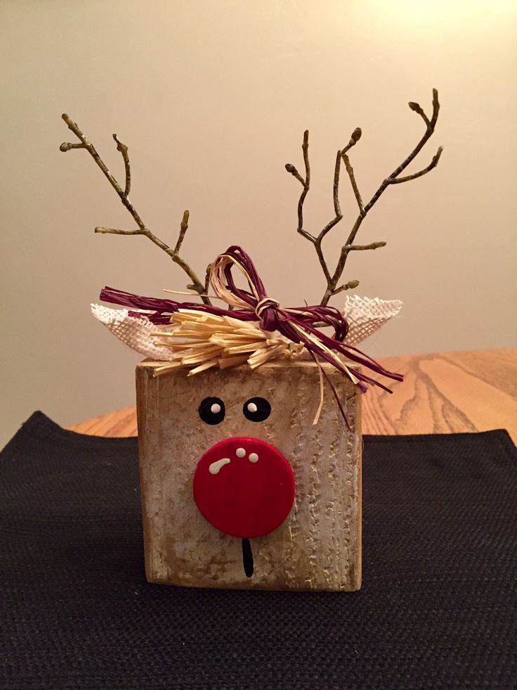 a small wooden block with a reindeer head on it's face and some branches sticking out of the top