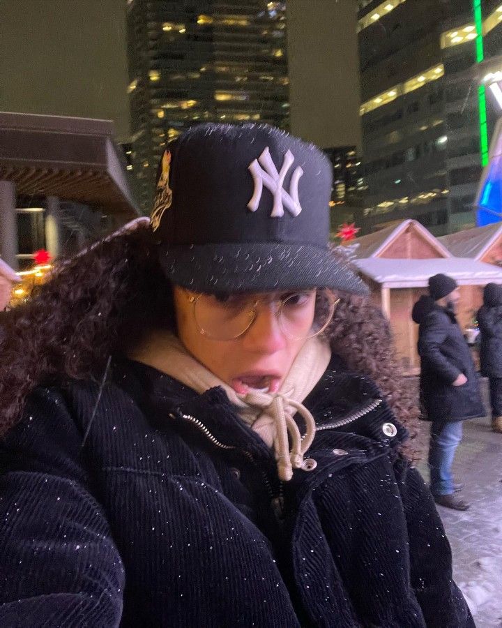 a woman wearing a new york yankees hat on her head while looking at her cell phone