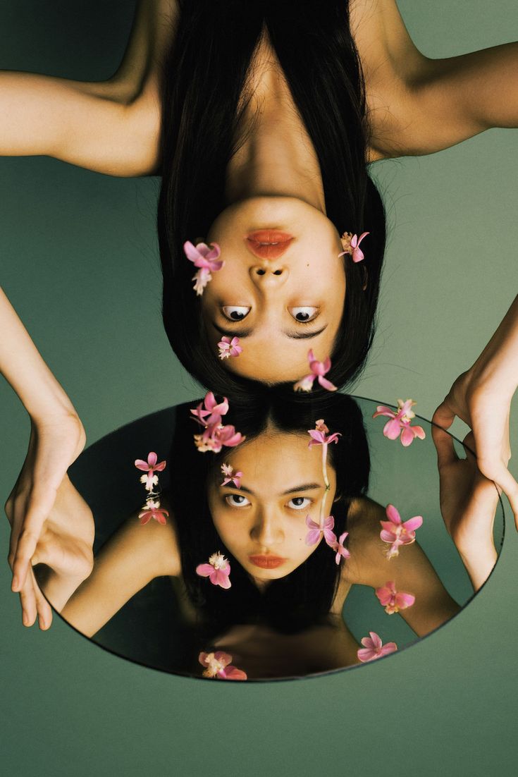 two women with flowers on their heads are reflected in a mirror that is upside down