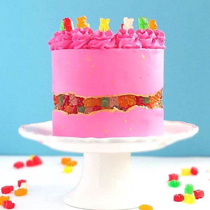 a pink birthday cake with gummy bears on top