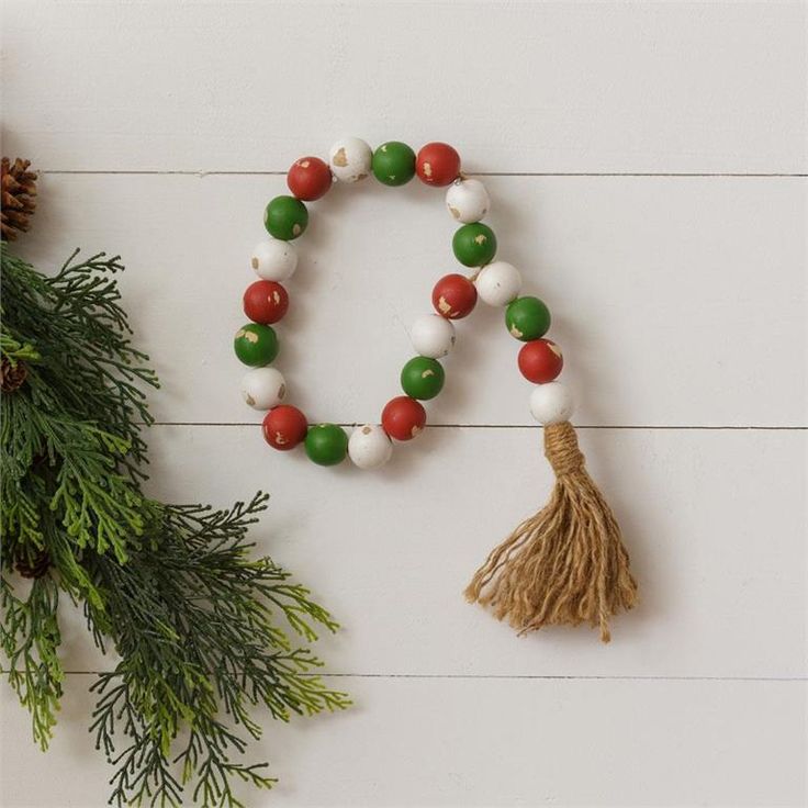 a tasseled christmas decoration with pine cones and red, white and green beads