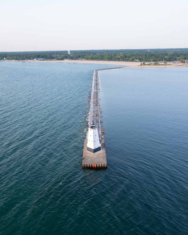 an aerial view of a long pier in the middle of the ocean with water surrounding it