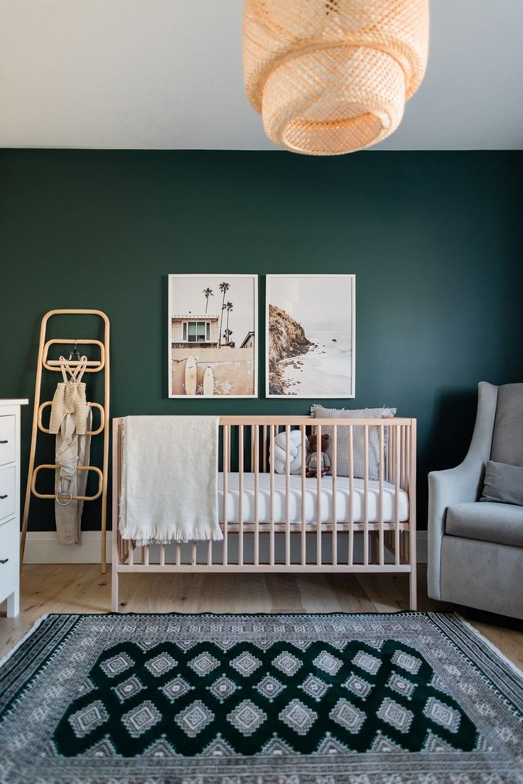 a baby's room with green walls and white crib in the corner, two pictures on the wall