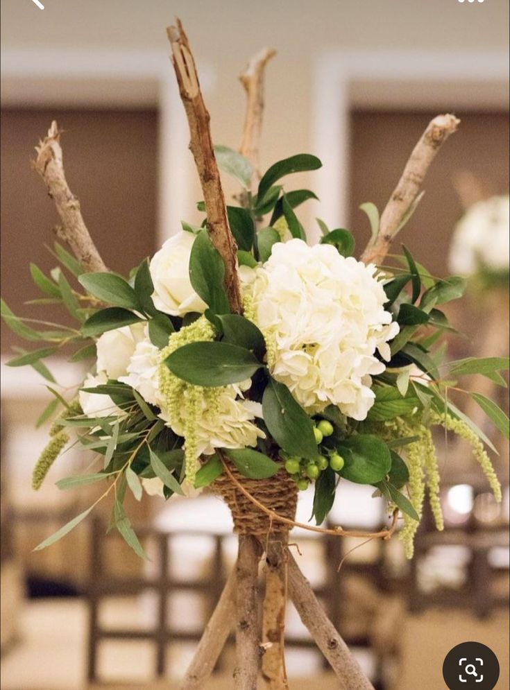 a vase filled with white flowers and greenery