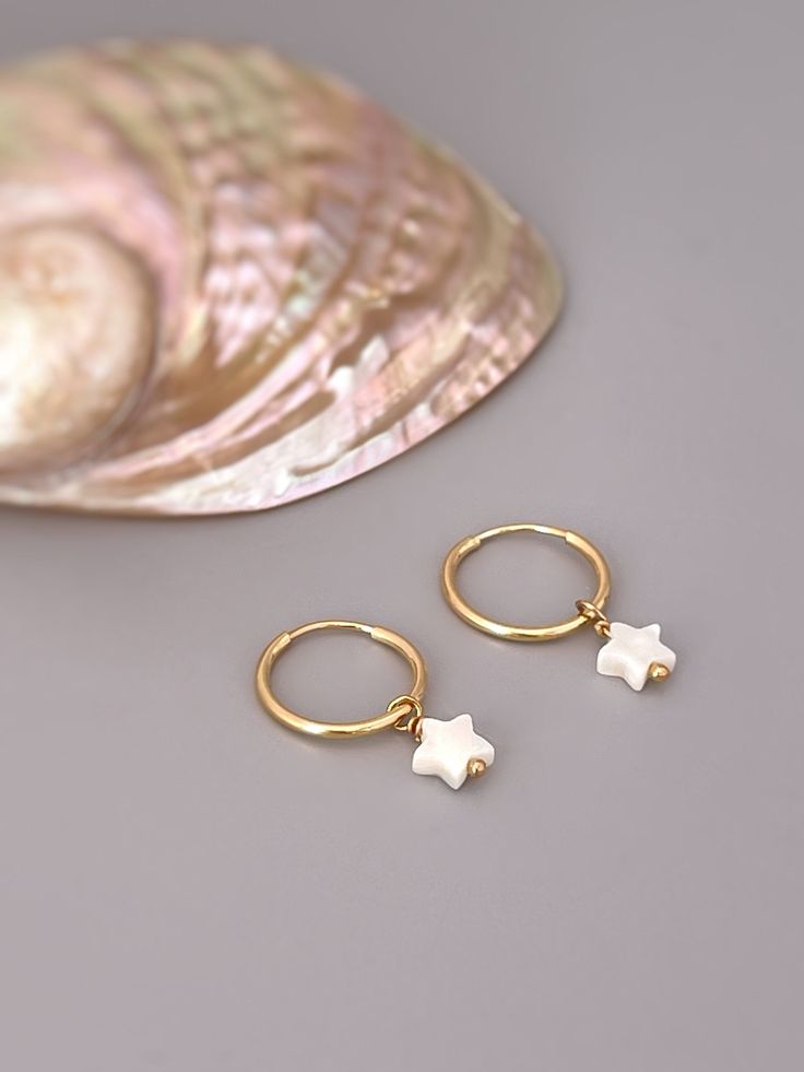 "Tiny Star hoop earrings. Handmade Mother of Pearl huggie Earrings.   Dainty Iridescent mother of pearl stars are set in your choice of 14k gold fill or sterling silver and hang 14mm endless hoops. Mother of Pearl stars are 6x6mm (about 1/4\" long).  Simple, elegant earrings perfect summer or beach wedding earrings for bridesmaids.  PLEASE note measurements and size reference pictures. Our jewelry and hair accessories are photographed close up to show detail and may appear larger than they are. Dainty White Earrings With Star Charm, Dainty White 14k Gold Filled Huggie Earrings, Small Hoop White Huggie Earrings In 14k Gold, White 14k Gold Filled Huggie Earrings, White Starfish Charm Earrings For Gift, White Starfish Charm Earrings As Gift, White Starfish Charm Earrings, White Star Charm Earrings As Gift, White Hypoallergenic Dangle Huggie Earrings