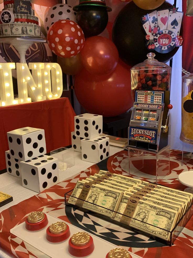 a casino themed birthday party with dice, cake and candy on a table in front of balloons