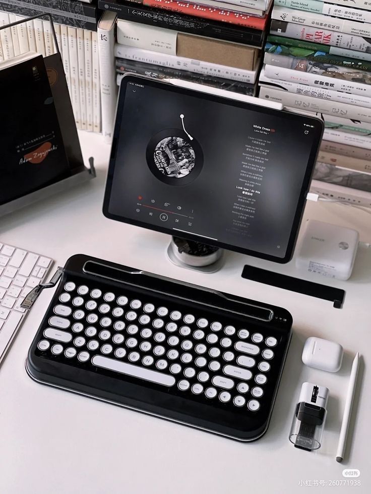 there is a keyboard and mouse on the desk next to an old typewriter in front of some books