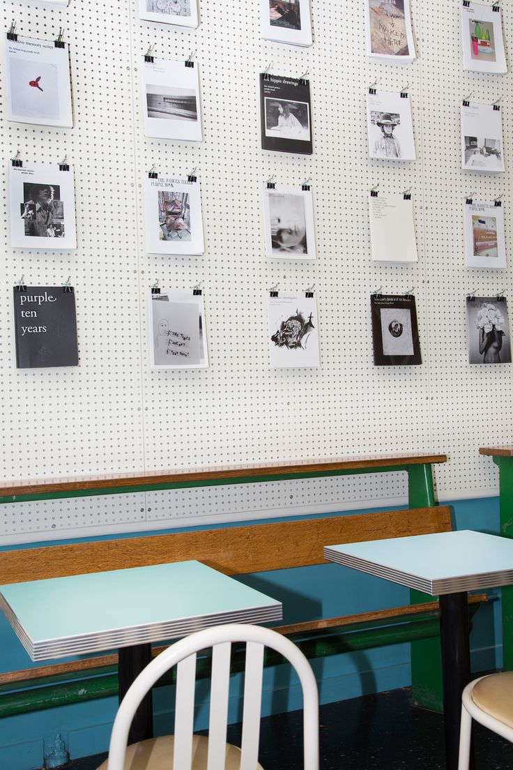 two tables and chairs in front of a wall with pictures on the wall behind them