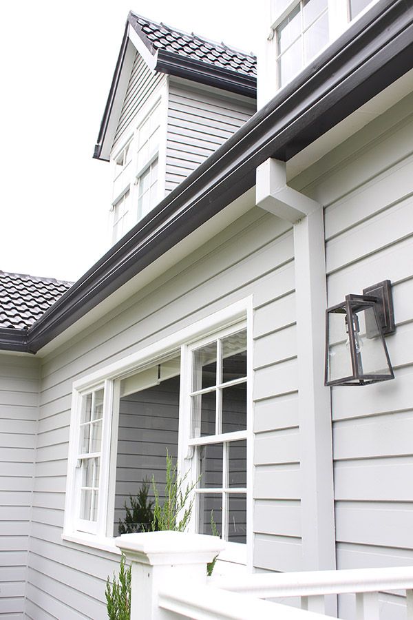 a house with white siding and black shingles on the roof, along with a large window