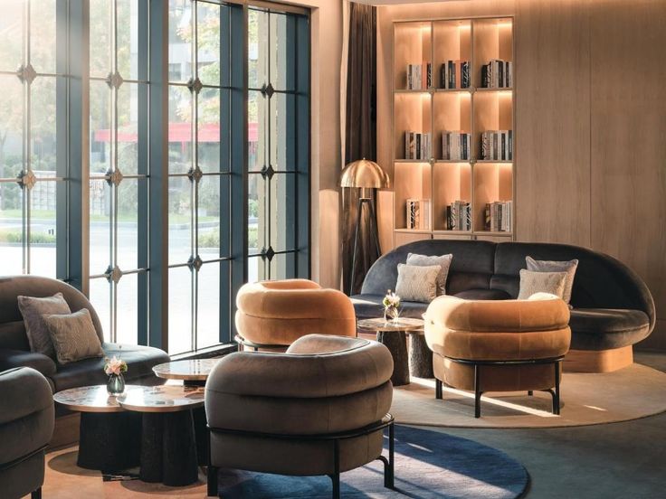 a living room filled with lots of furniture and bookshelves on the wall next to large windows