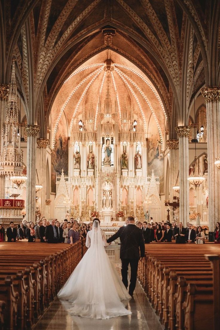 a bride and groom walking down the aisle at their wedding ceremony in an ornate cathedral