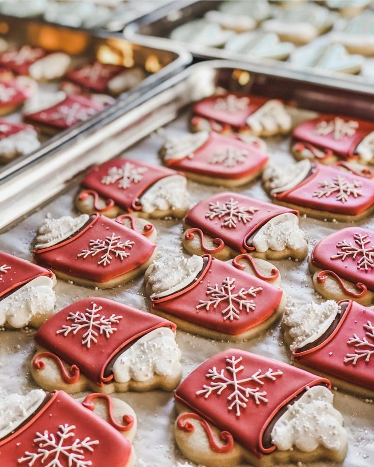 cookies decorated with red and white icing are on a tray in front of other cookies