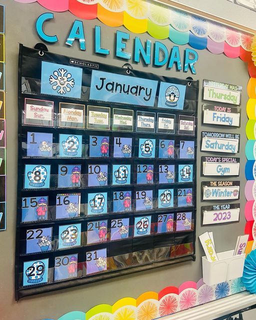 a calendar is displayed on the wall in front of colorful paper fan garlands and balloons