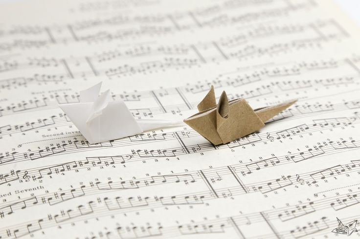 two origami birds sitting on top of sheet music