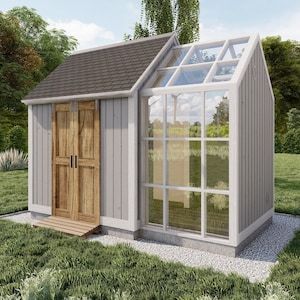 a small white shed with a wooden door and windows on the side, in a grassy area