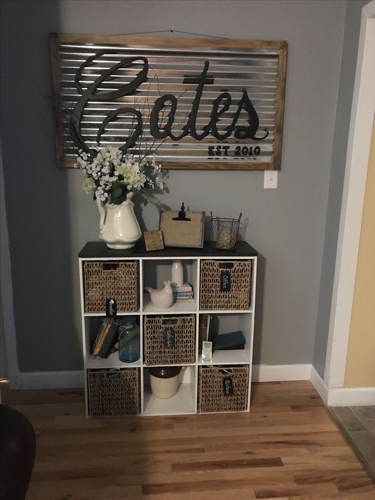 a shelf with baskets and flowers in it next to a sign that says cats on the wall