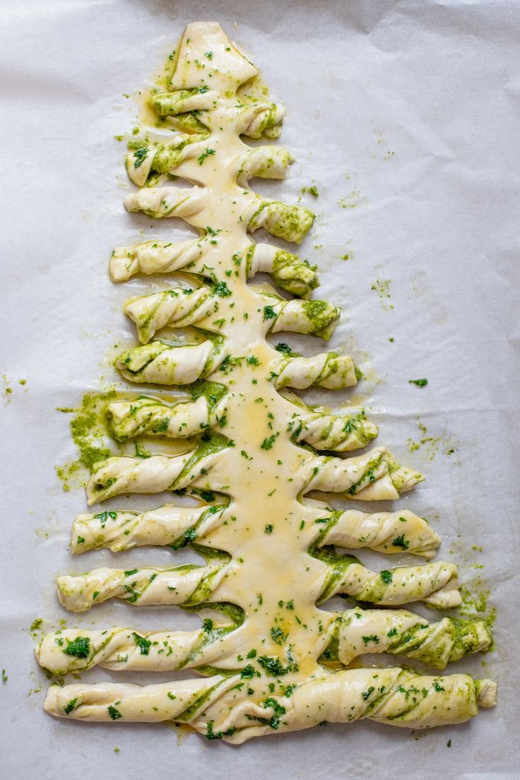 a christmas tree shaped pizza sitting on top of a white paper covered in cheese and sauce