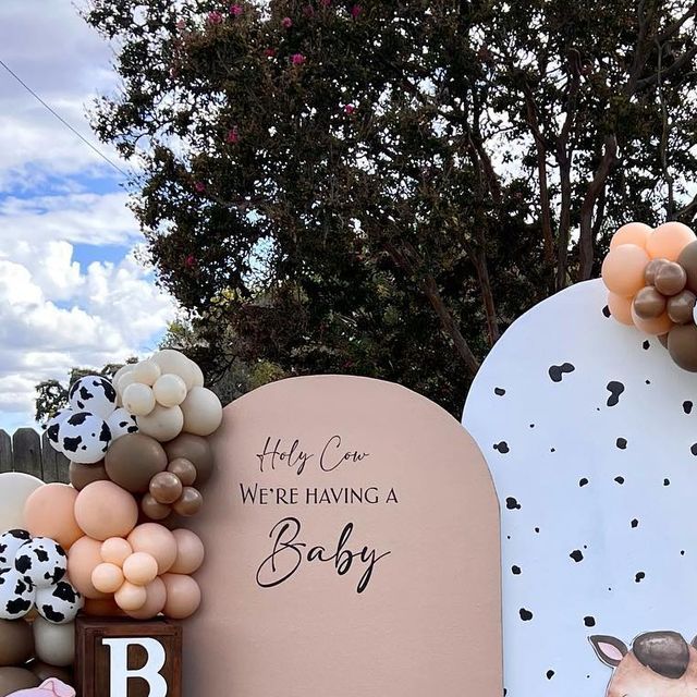 there is a sign that says, hey one we're having a baby and balloons in the shape of animals