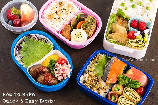 four bento boxes filled with different types of food and vegetables on top of a wooden table