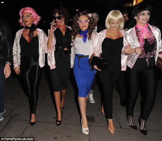 four women dressed in costumes walking down the street at night with one woman wearing pink hair