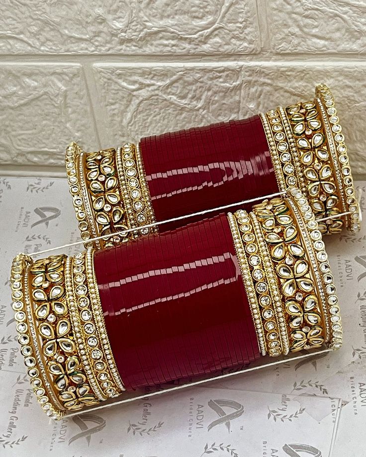 two red and gold bangles sitting on top of a white table next to each other