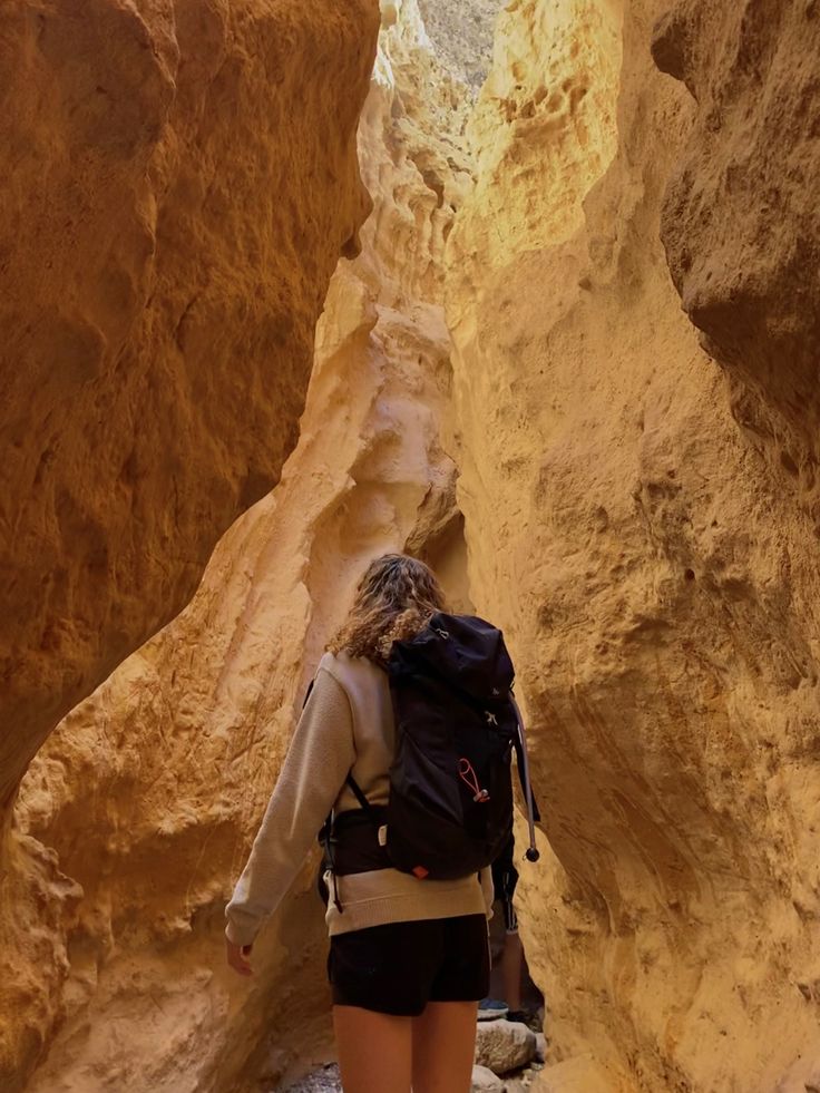 a woman hiking through a narrow canyon in the desert