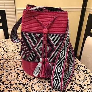 a pink and black bag sitting on top of a table next to a white chair