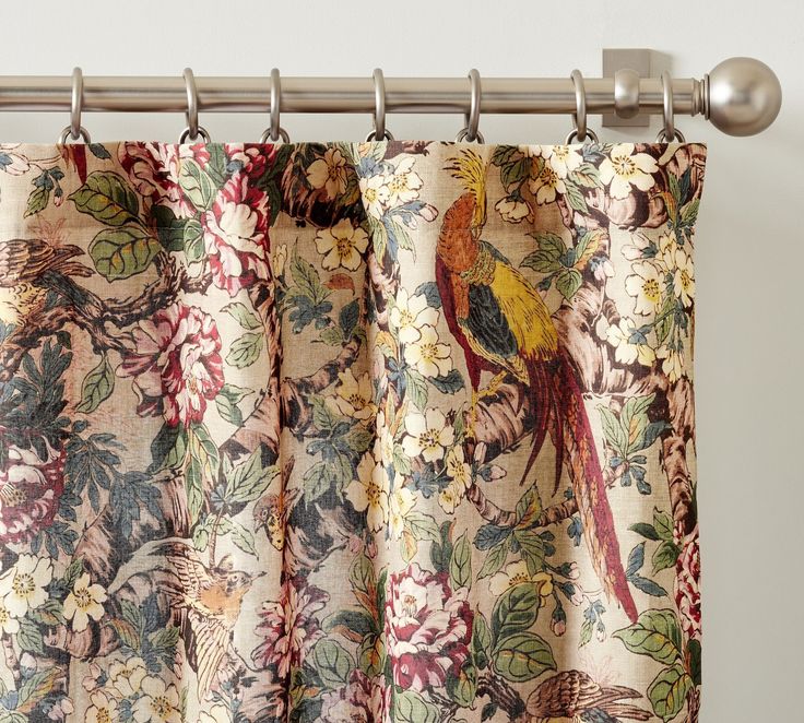 a curtain with a bird and flowers pattern hanging from it's metal rod ends