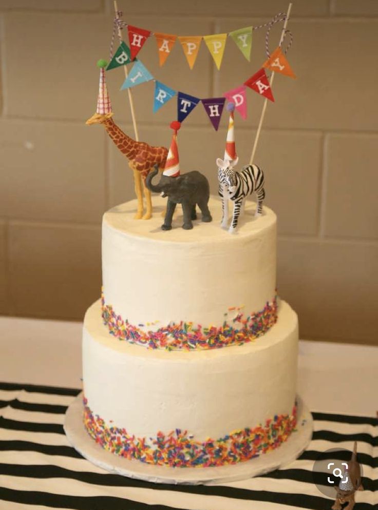 a birthday cake with an animal and zebra topper on the bottom is decorated with colorful streamers