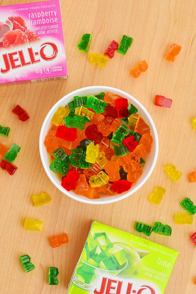 a bowl of gummy bears sitting on top of a table next to a box of jello