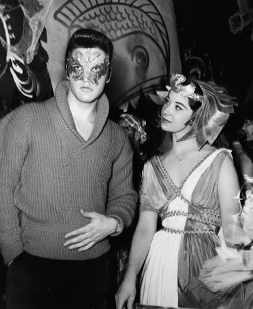 a man standing next to a woman wearing a mask