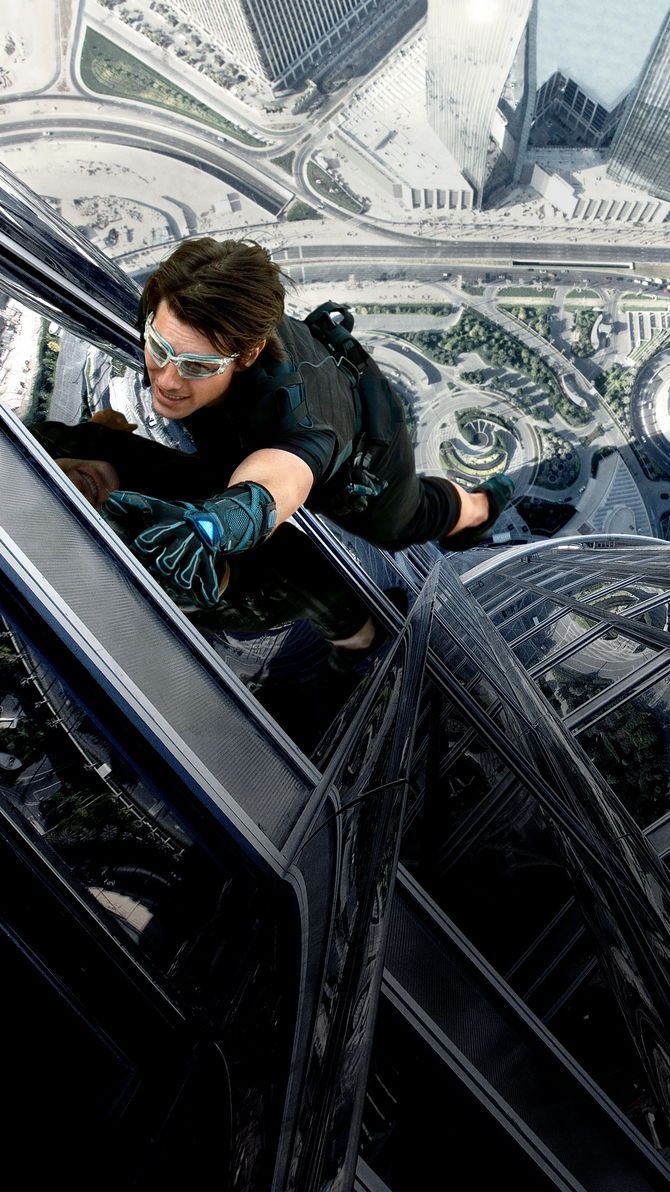 a man in black jacket and goggles climbing up an escalator with cityscape behind him