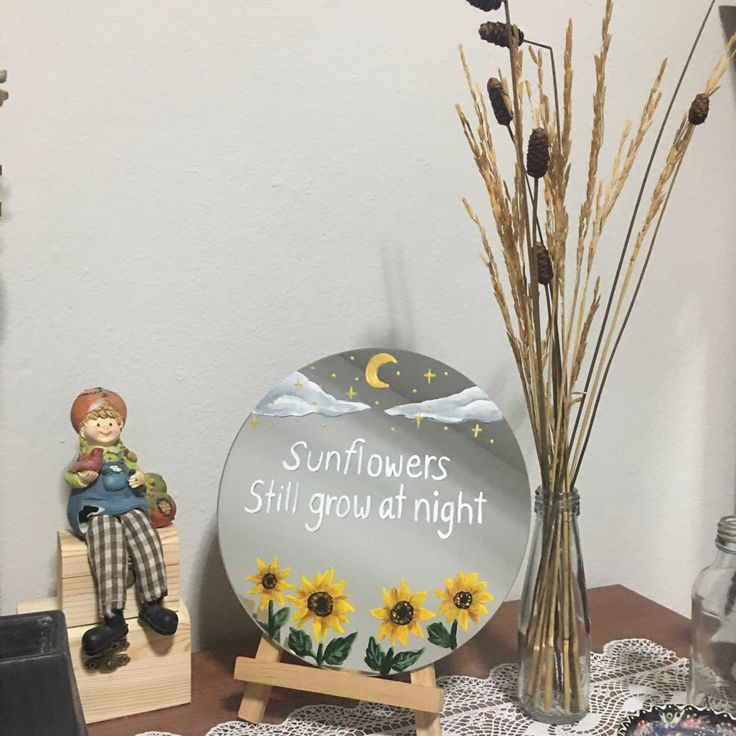 a sunflowers still grow at night sign next to a vase with dried flowers