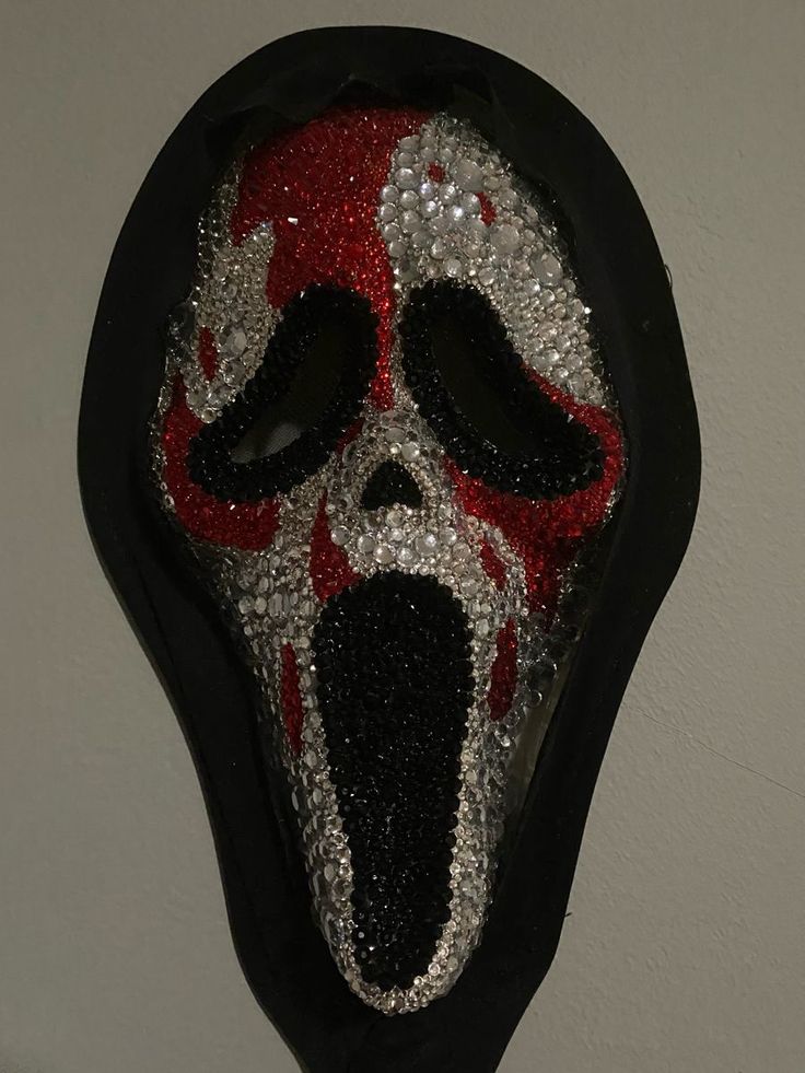 a red and black mask hanging on the wall with its mouth open in front of it