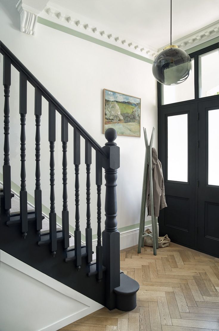 a black and white staircase leading up to a door with a painting on the wall