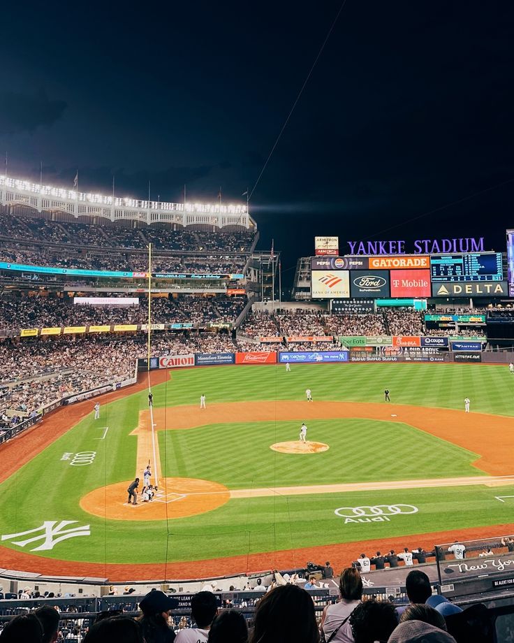 a baseball stadium filled with lots of people sitting in the bleachers at night