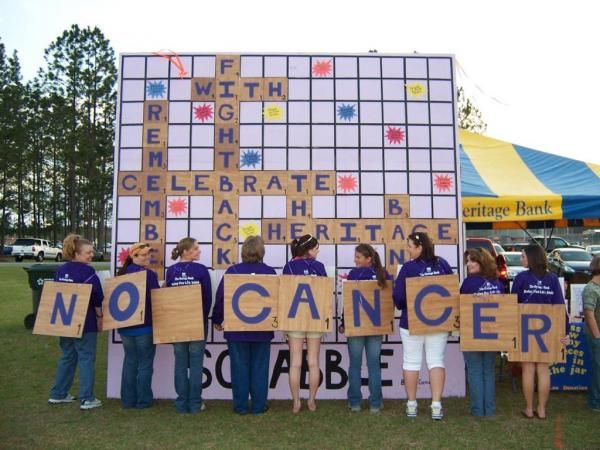 a group of people holding signs in front of a giant scrabble board