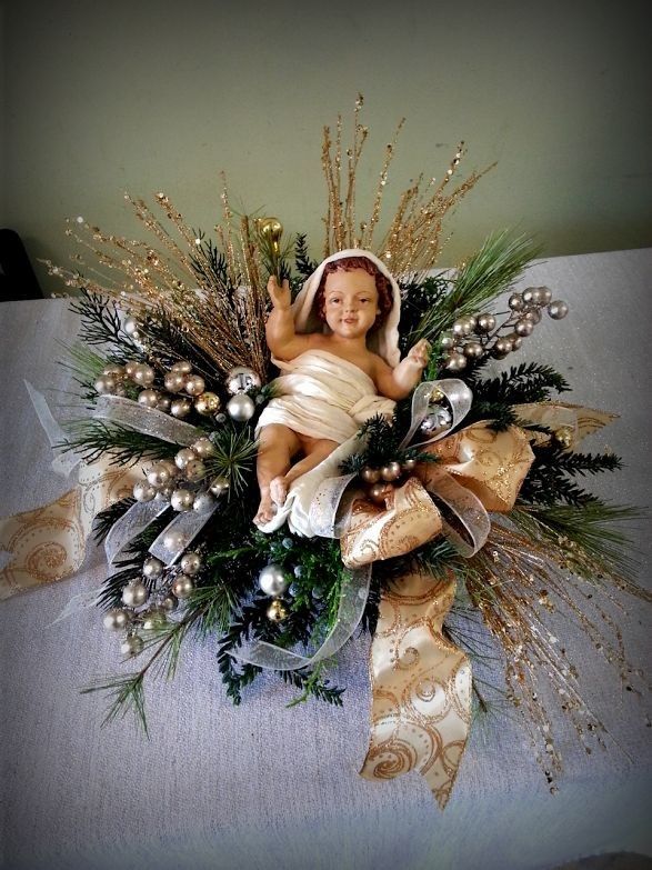 a baby doll sitting on top of a christmas wreath