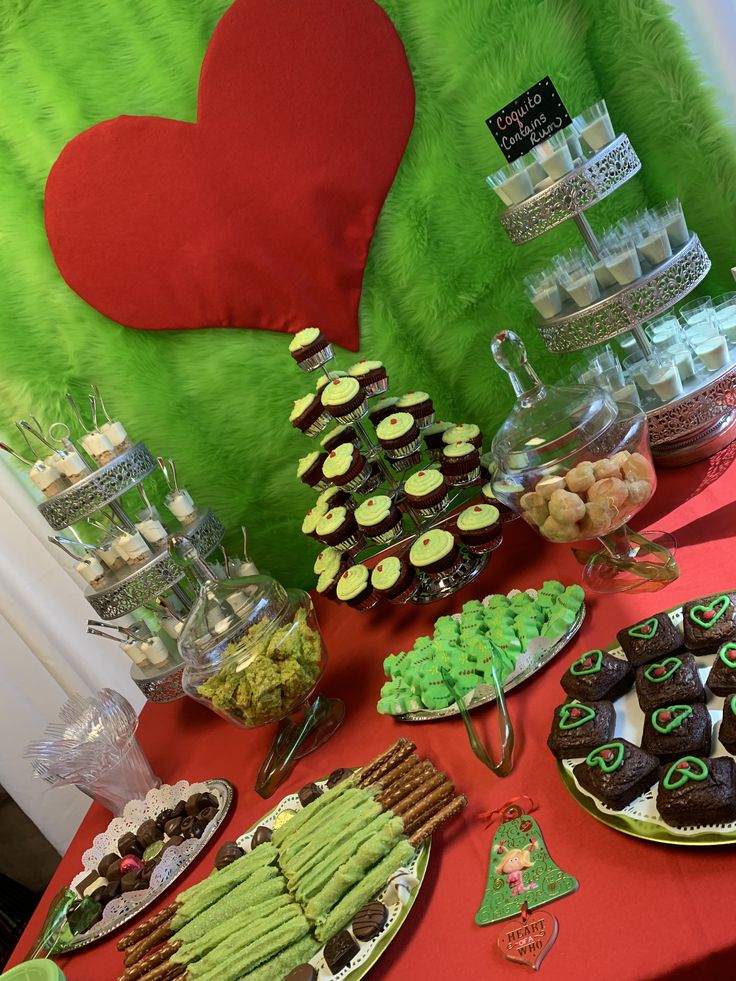 a table topped with lots of desserts next to a green heart shaped pillow on top of a chair