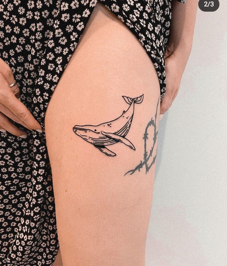 a woman's thigh with a tattoo of a humpback whale on it