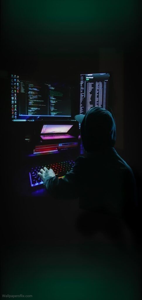 a person sitting at a computer in the dark