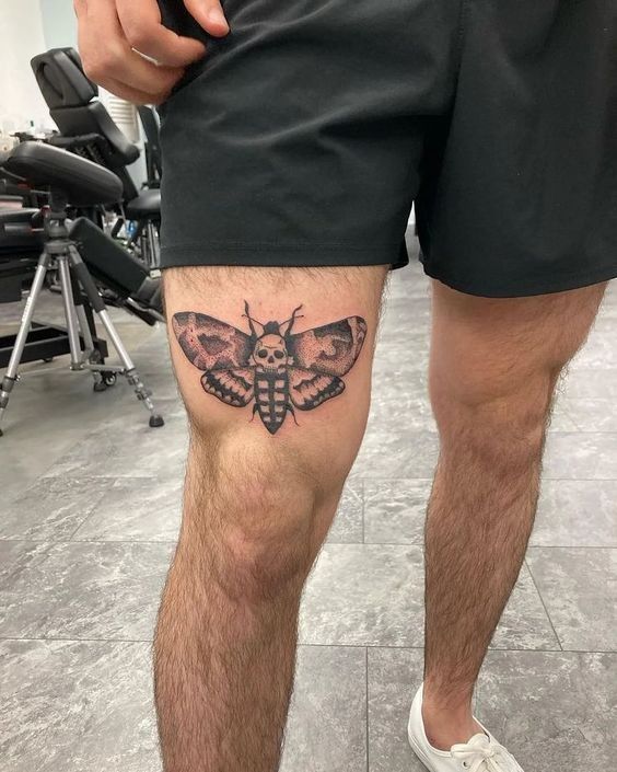 a man's leg with a moth tattoo on the lower half of his leg