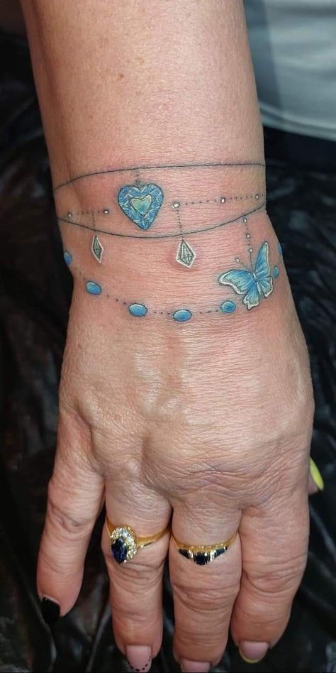 a woman's hand with tattoos on it and butterflies attached to the bracelets