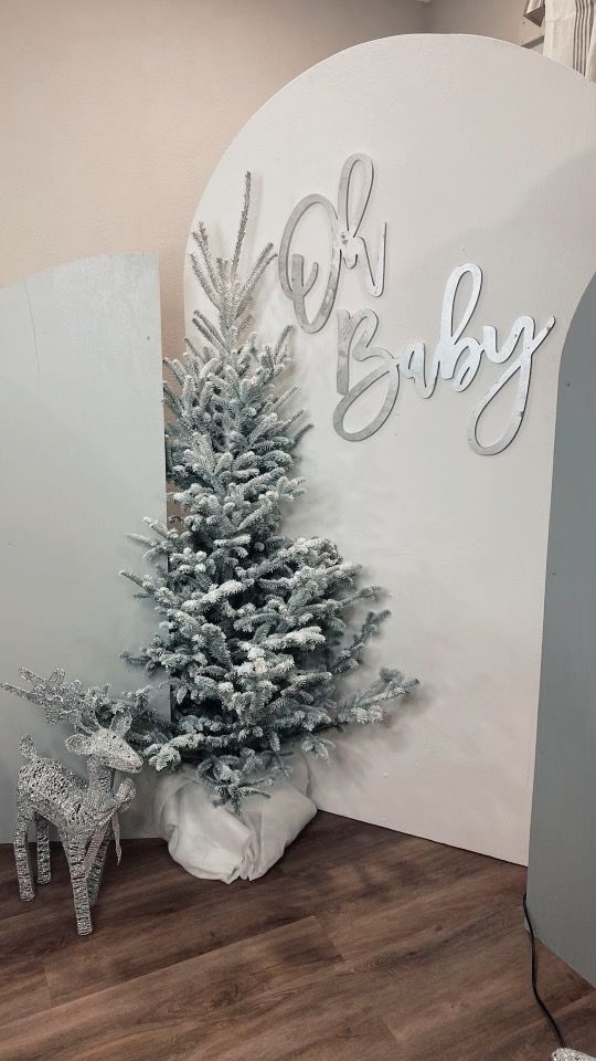 a small christmas tree sitting in front of a sign that says oh baby on it