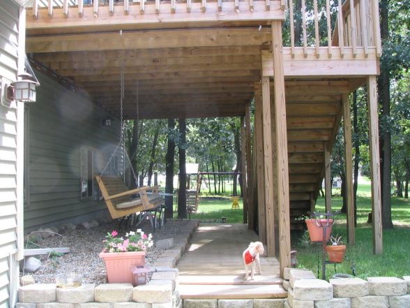 a dog is sitting on the porch in front of a house