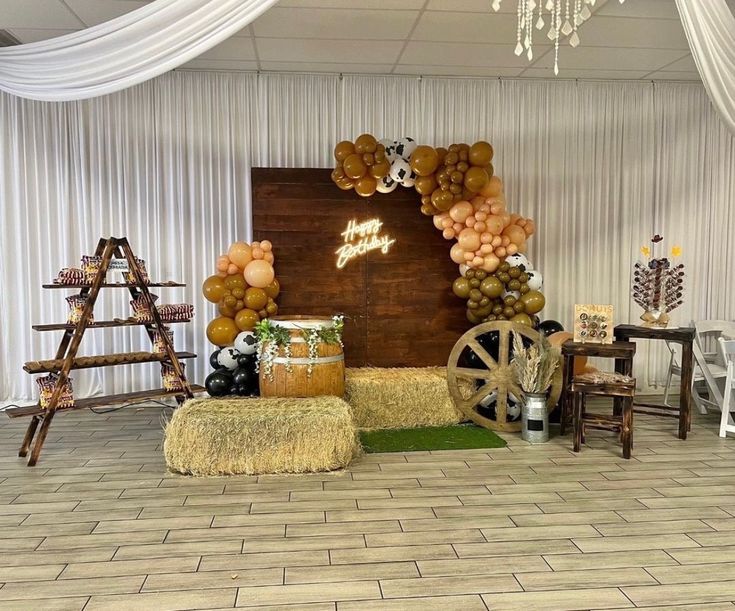 a decorated stage with hay bales and balloons on the wall, along with other decorations